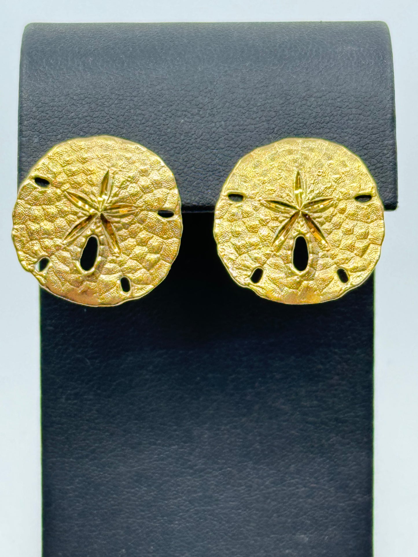 14K yellow gold sand dollar stud earrings with textured discs and cutouts.