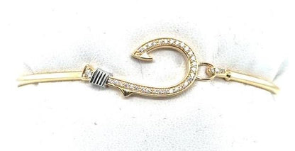Yellow gold bangle with diamond‑pavé fish hook and white gold wrapped detail.