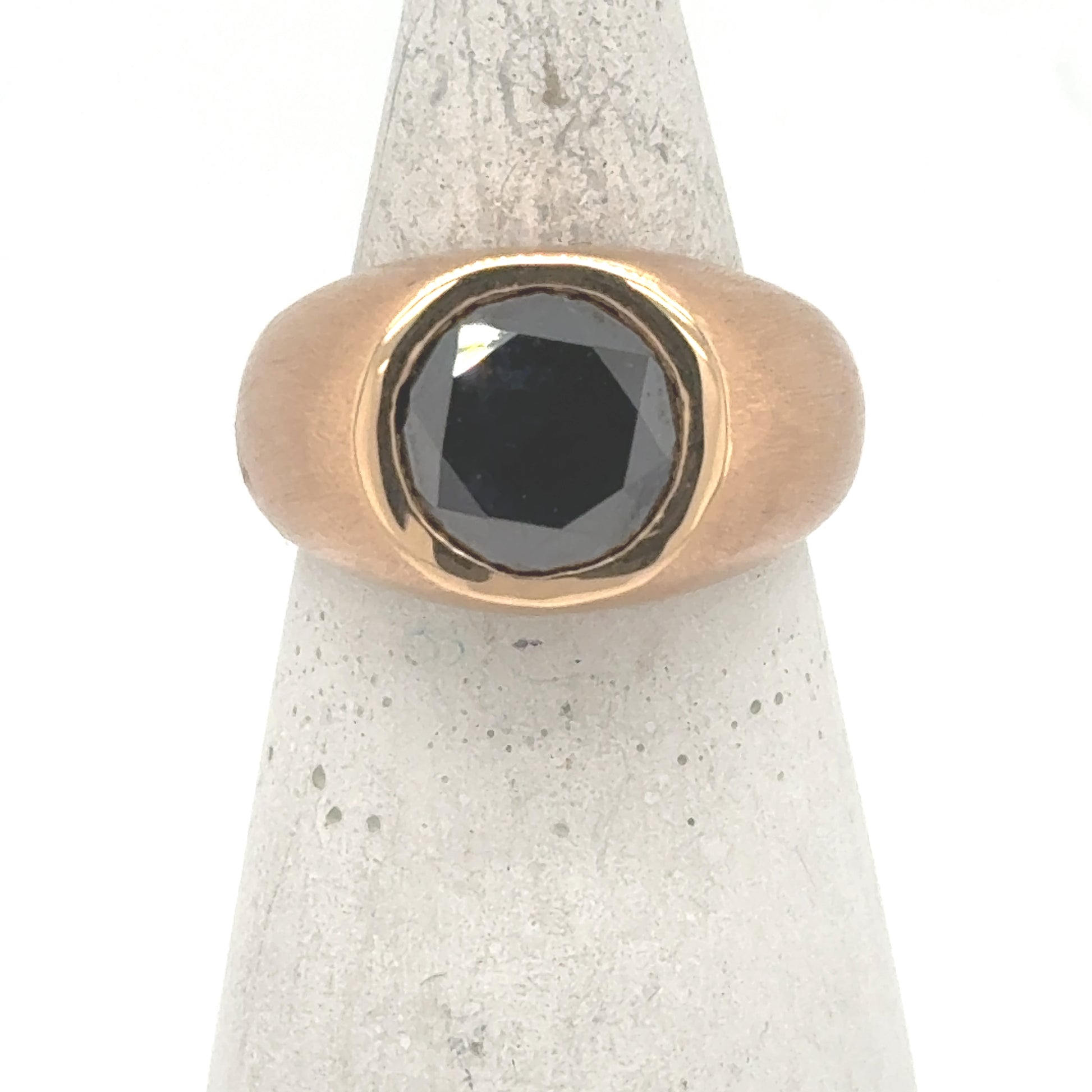 18K rose gold ring with bezel-set round black diamond on wide band.