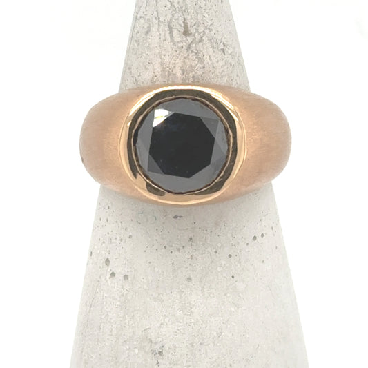 18K rose gold ring with bezel-set round black diamond on wide band.