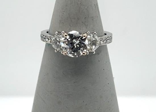 18K white gold ring with round center diamond, flanked by tapered side stones and pavé band.