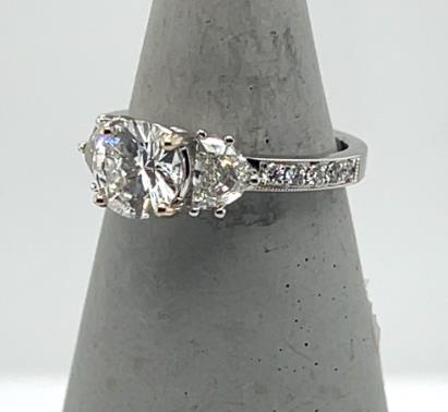 18K white gold ring with round center diamond, tapered side diamonds, and pavé band.