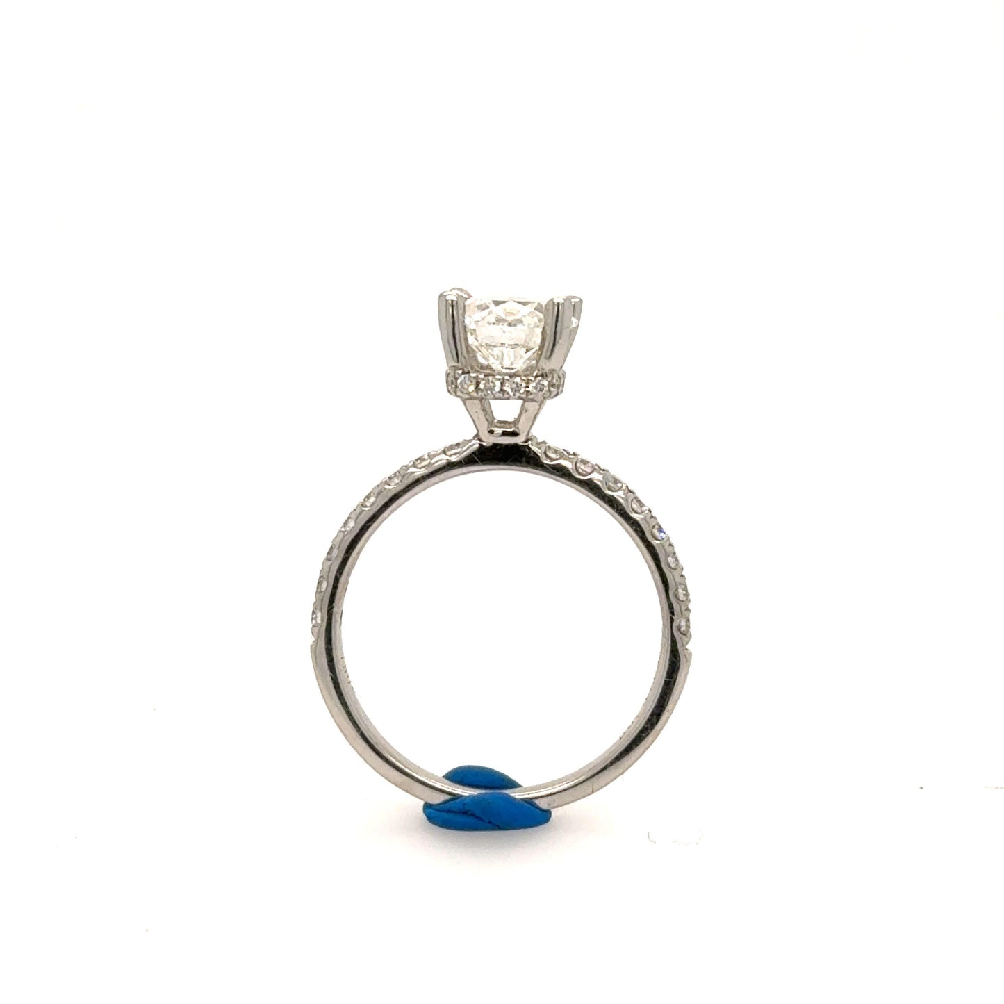 White gold engagement ring with round solitaire in four-prong setting and pavé band.