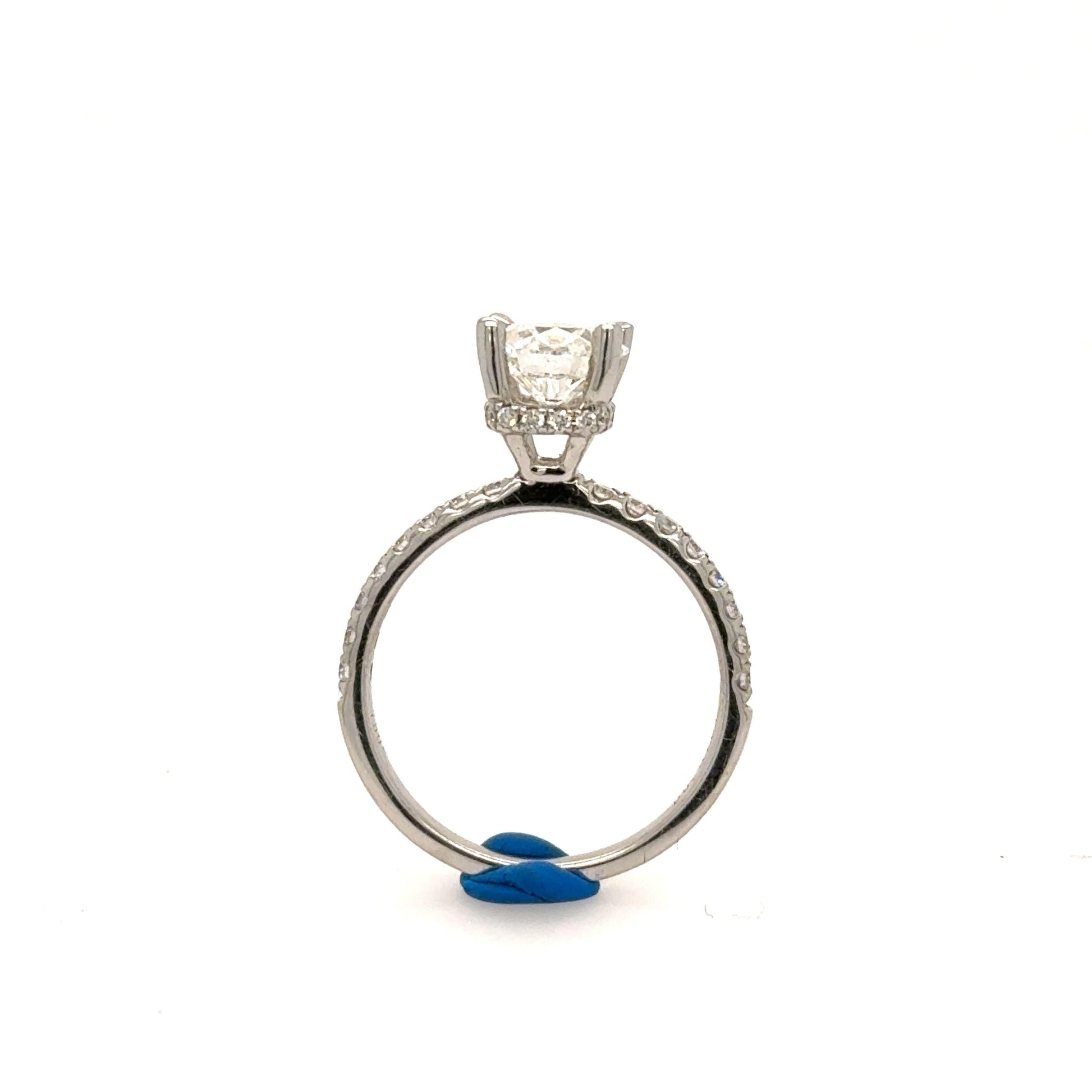 White gold engagement ring with round solitaire in four-prong setting and pavé band.