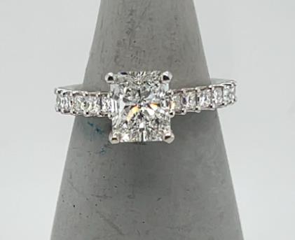 18K white gold ring with radiant-cut diamond and princess-cut diamond band.
