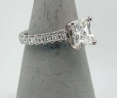 18K white gold ring with radiant-cut diamond and prong-set princess-cut side stones.