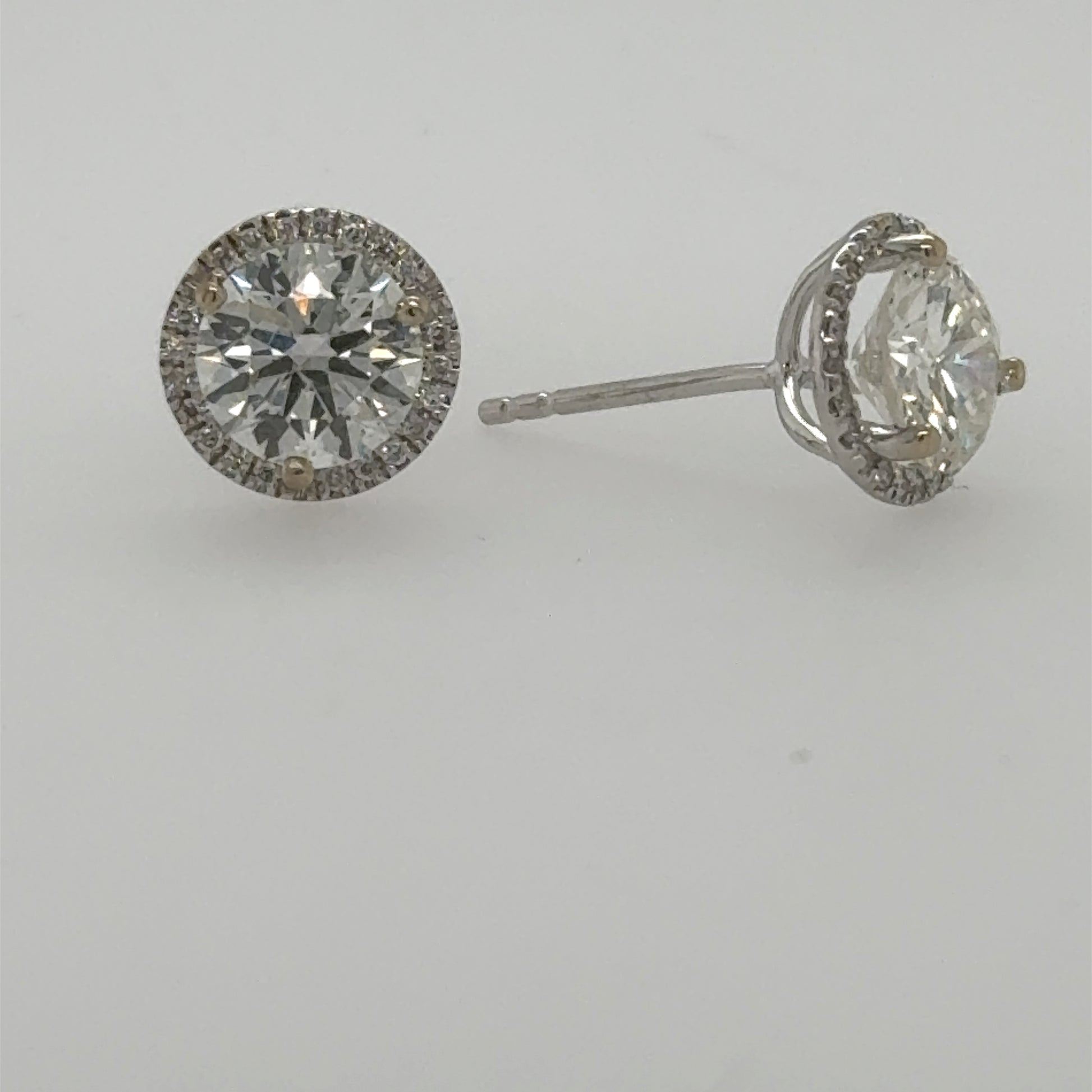 18K white gold stud earrings with round center diamonds and halo.