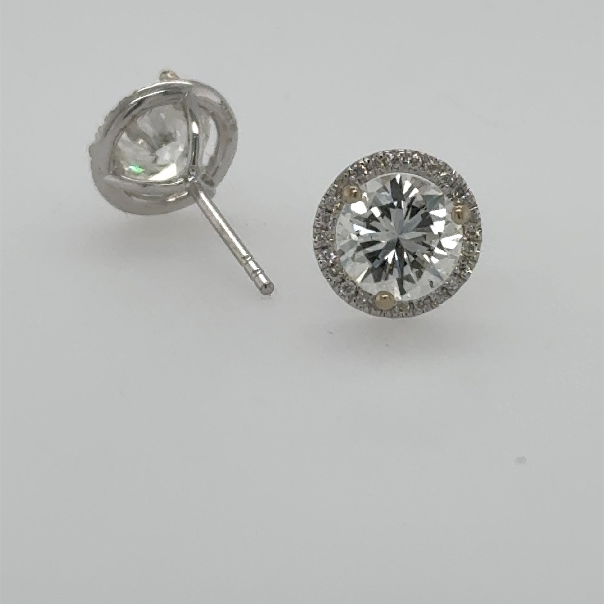 18K white gold diamond stud earrings with round center stones and halo, friction posts.