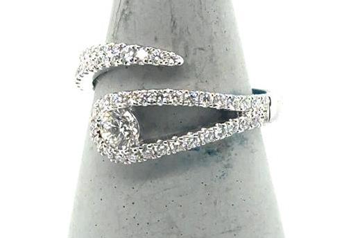 18K white gold bypass ring with pave diamonds and a channel-set round center.