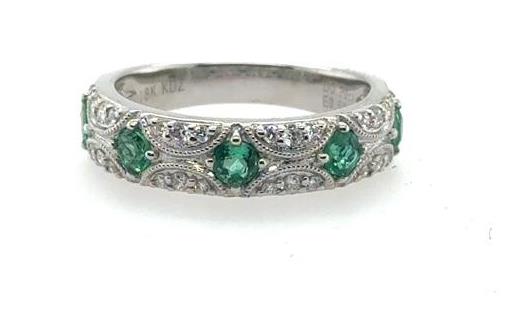 18K white gold band with five round green emeralds and pavé diamond accents.