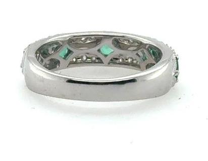 18K white gold band with prong-set emeralds and small round diamonds.