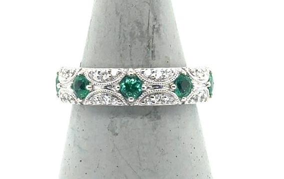 18K white gold band with round green emeralds and pavé diamond accents.