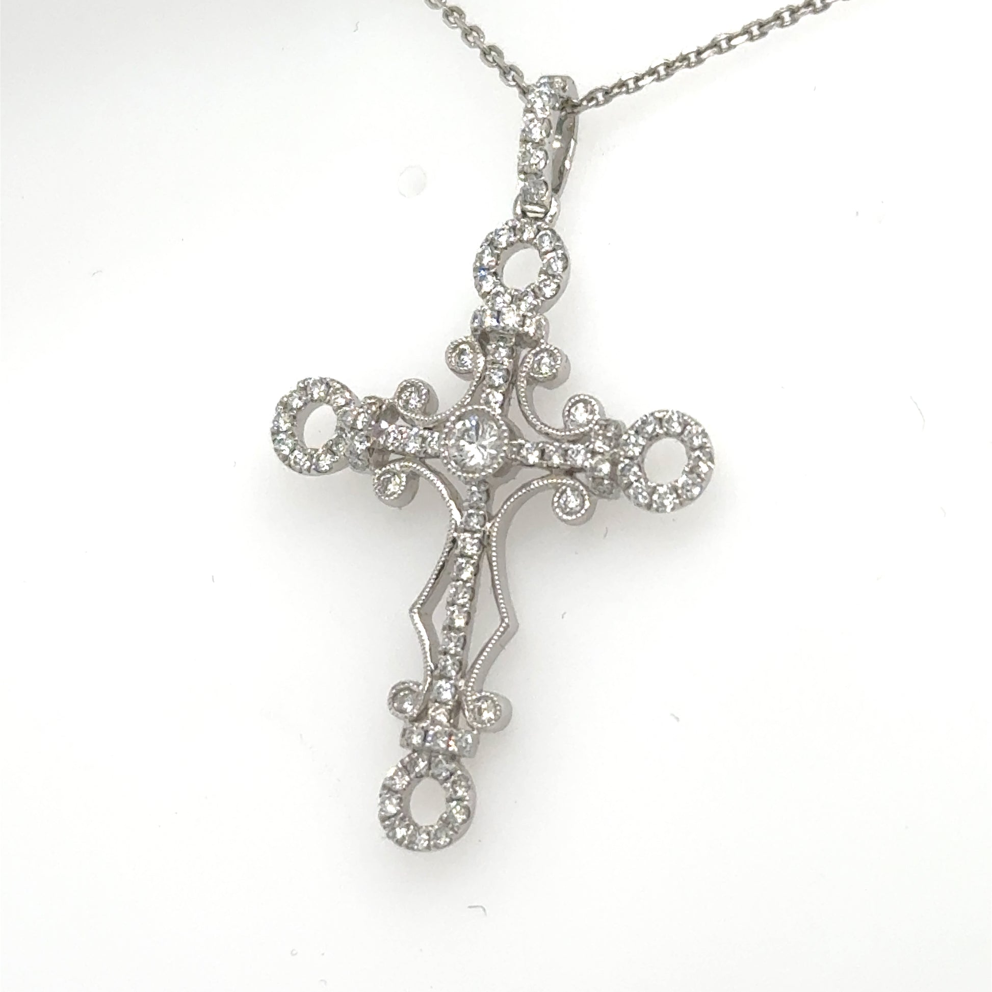 18K white gold diamond cross pendant with ornate loops on 14K chain.