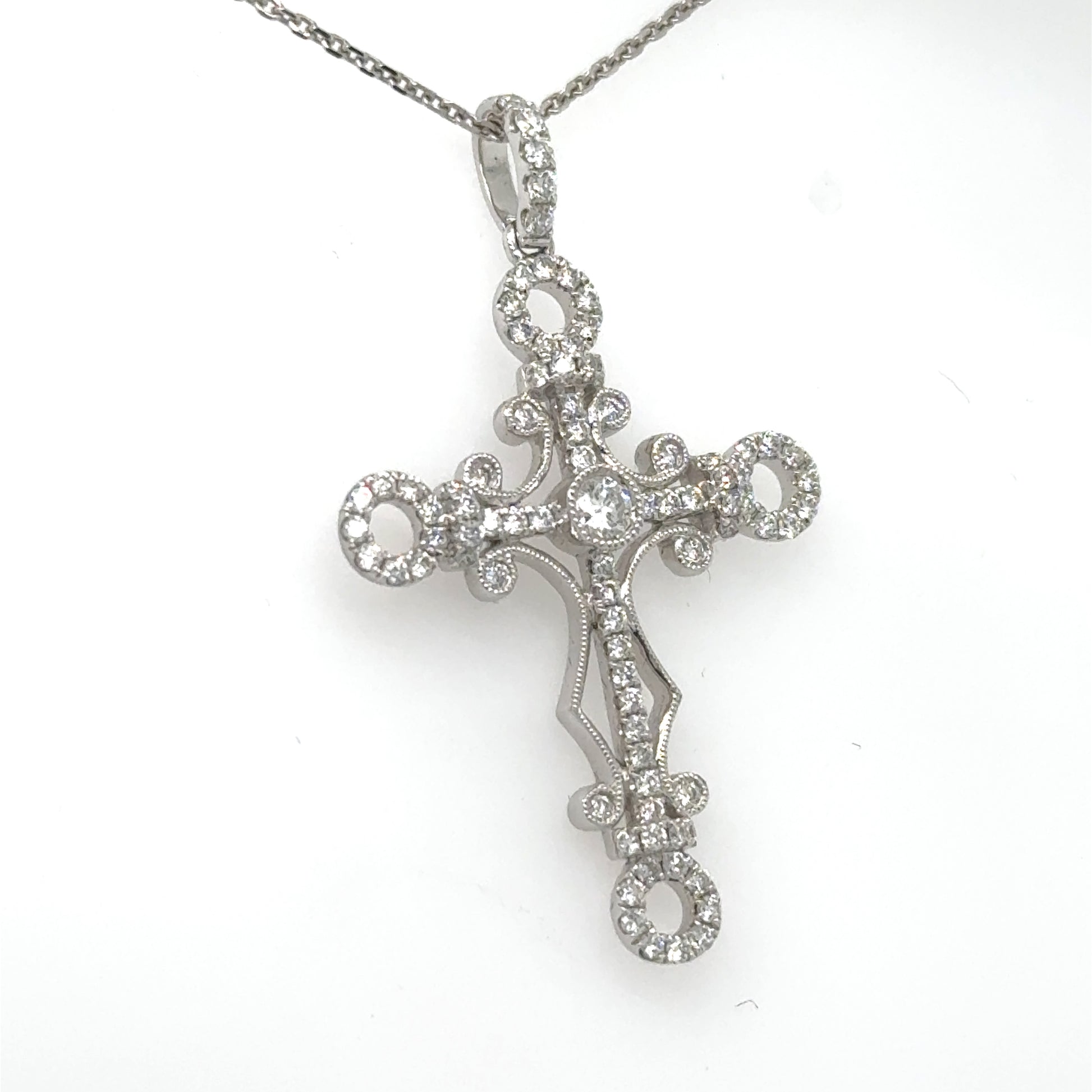 18K white gold diamond cross pendant with ornate openwork and diamond bail on chain.