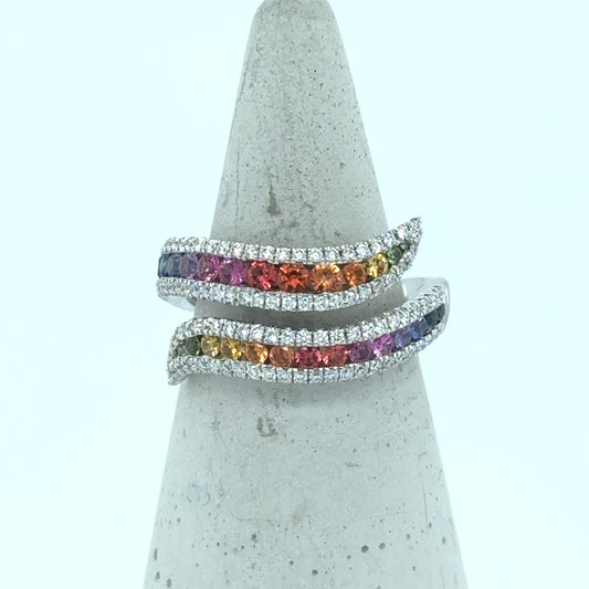18K white gold bypass ring with graduated rainbow sapphires and diamond borders.