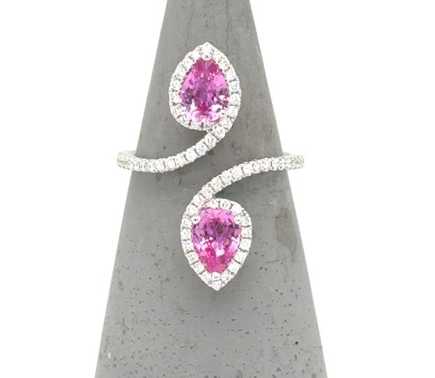 18K white gold bypass ring with two pear-cut pink sapphires and diamond halos.