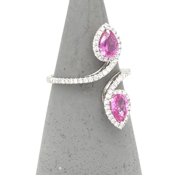 18K white gold bypass ring with two pear-cut pink sapphires and diamond halos.