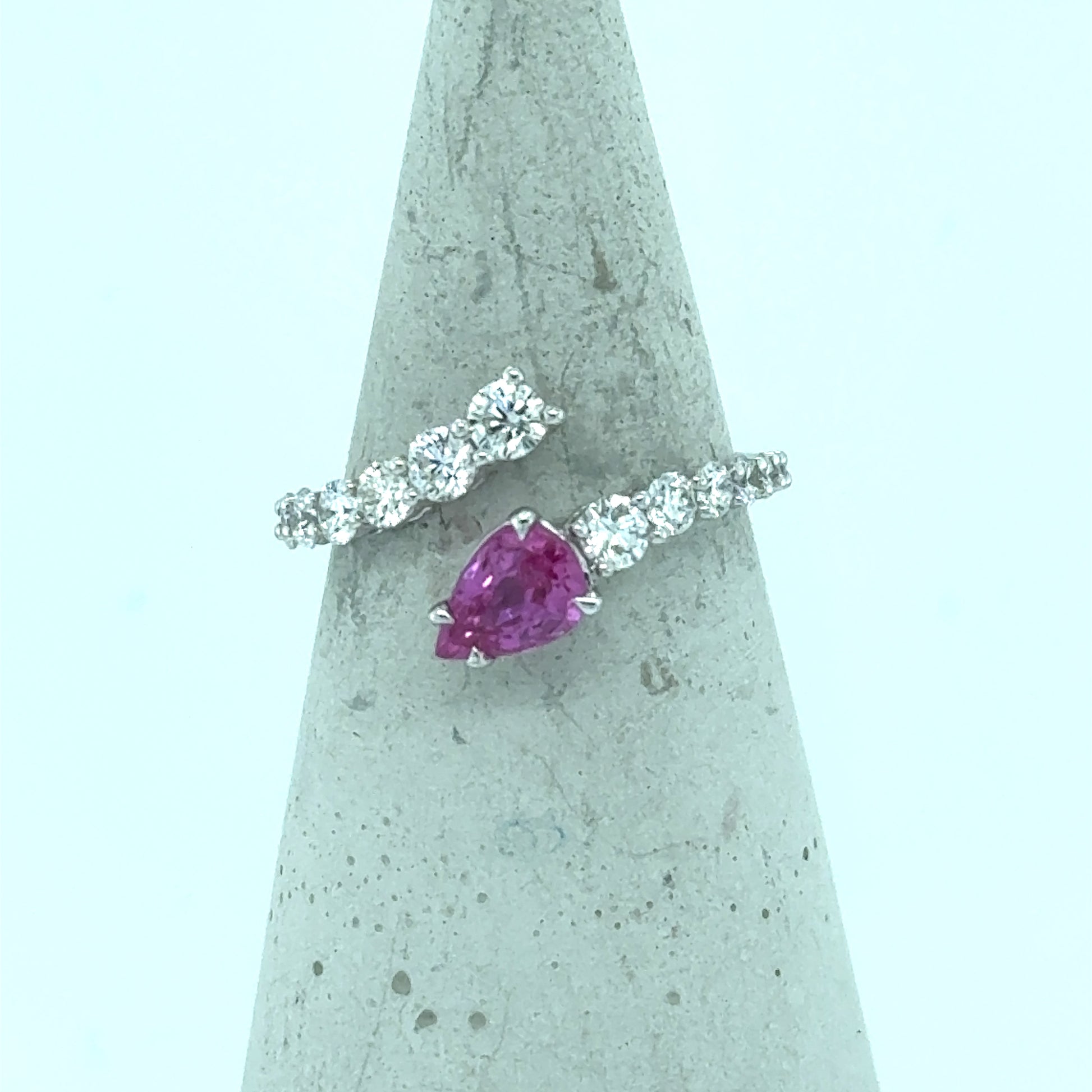 18K white gold bypass ring with pear-cut pink sapphire and diamond band.