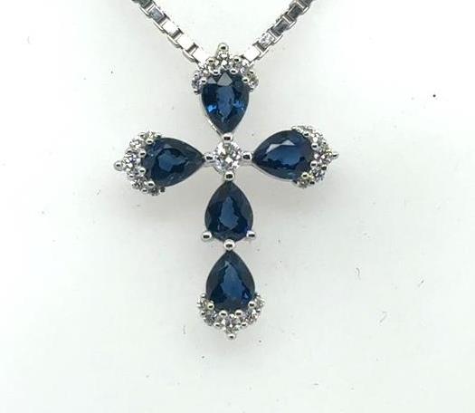 White gold cross pendant with five pear-cut blue sapphires and small diamonds.