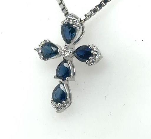 White gold cross pendant with five pear-cut blue sapphires and small round diamonds.