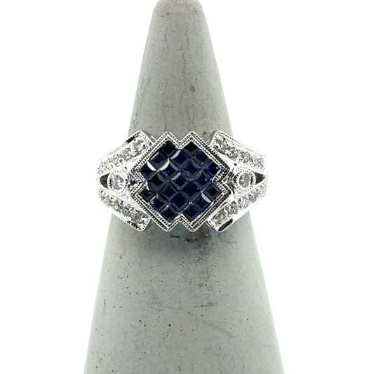 18K white gold ring with square-set blue sapphires and diamond-accented shoulders.