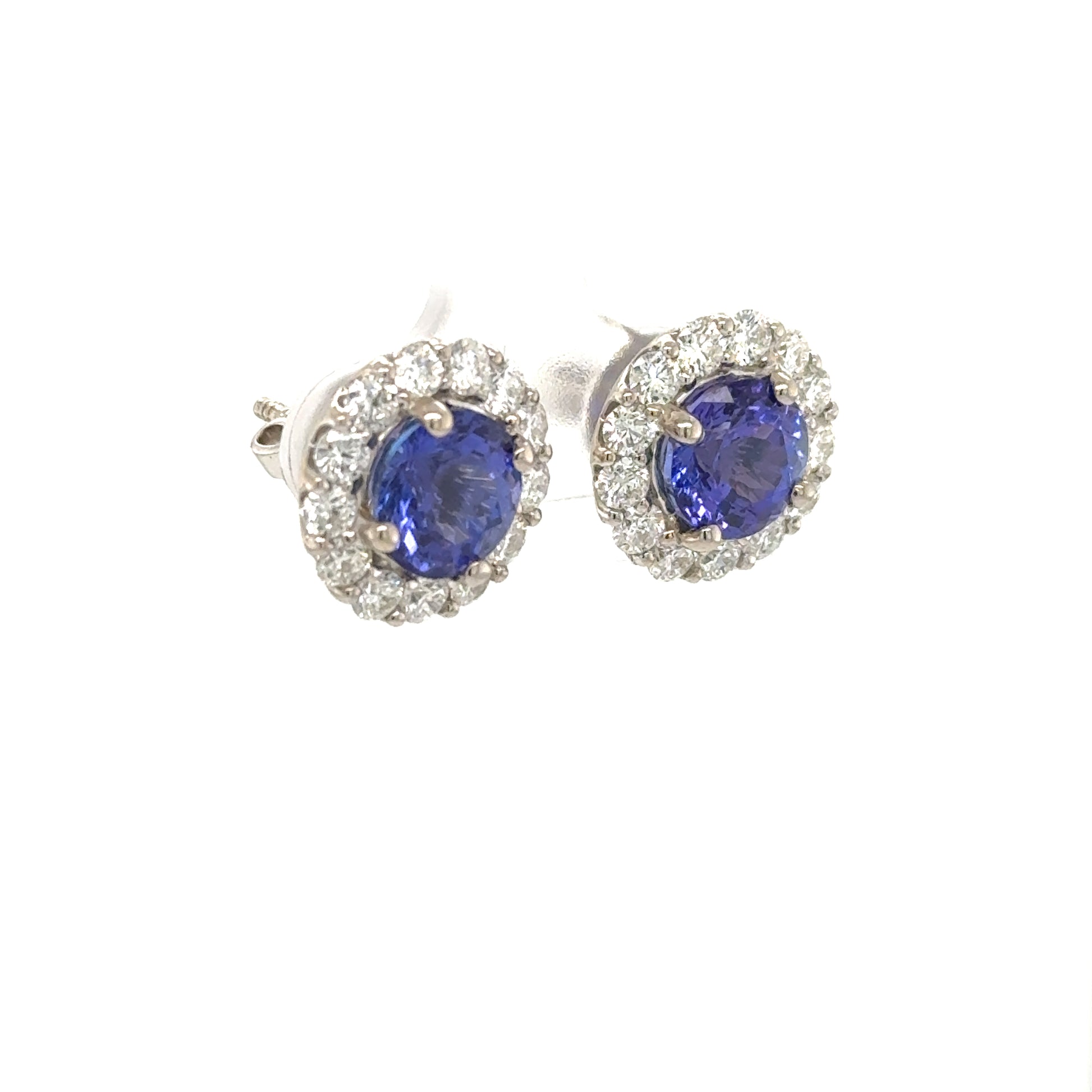 18K white gold stud earrings with round blue tanzanites and diamond halos.