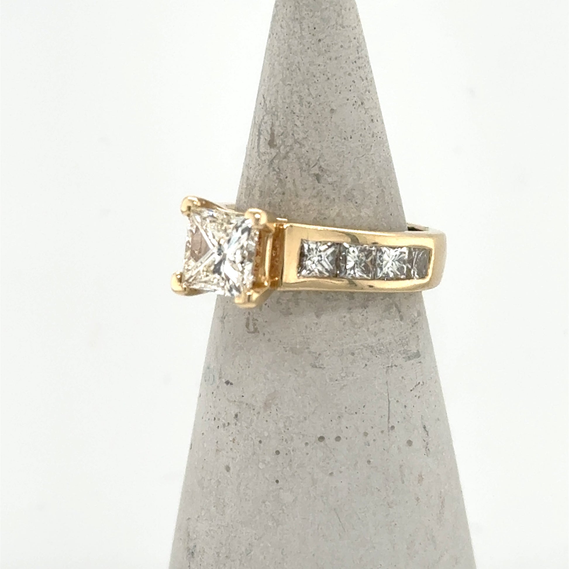 14K yellow gold ring with princess-cut center diamond and channel-set side stones.