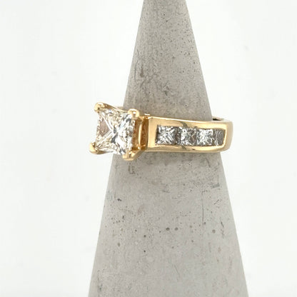 14K yellow gold ring with princess-cut center diamond and channel-set side stones.
