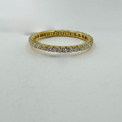 18K yellow gold eternity band with round diamonds in four-prong continuous setting.