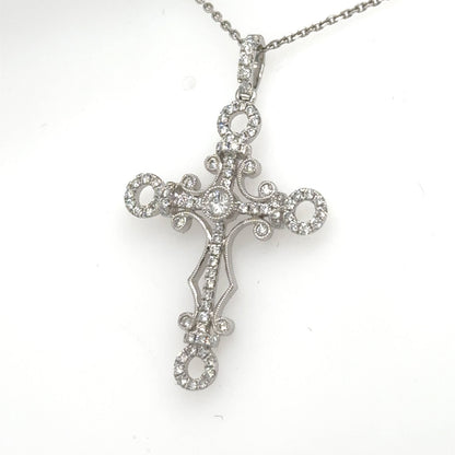 18K white gold diamond cross pendant with ornate loops on 14K chain.