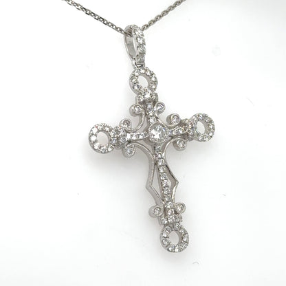 18K white gold diamond cross pendant with ornate openwork and diamond bail on chain.