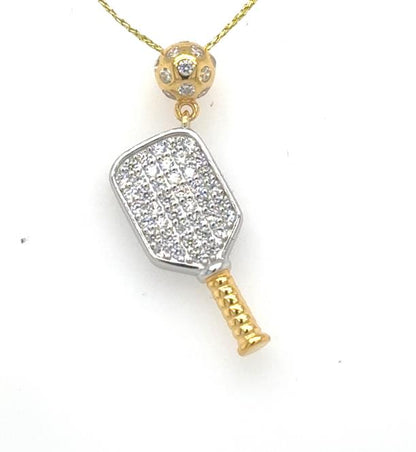 Two-tone pickleball paddle pendant with CZ pavé face, gold handle, and perforated gold ball bail.
