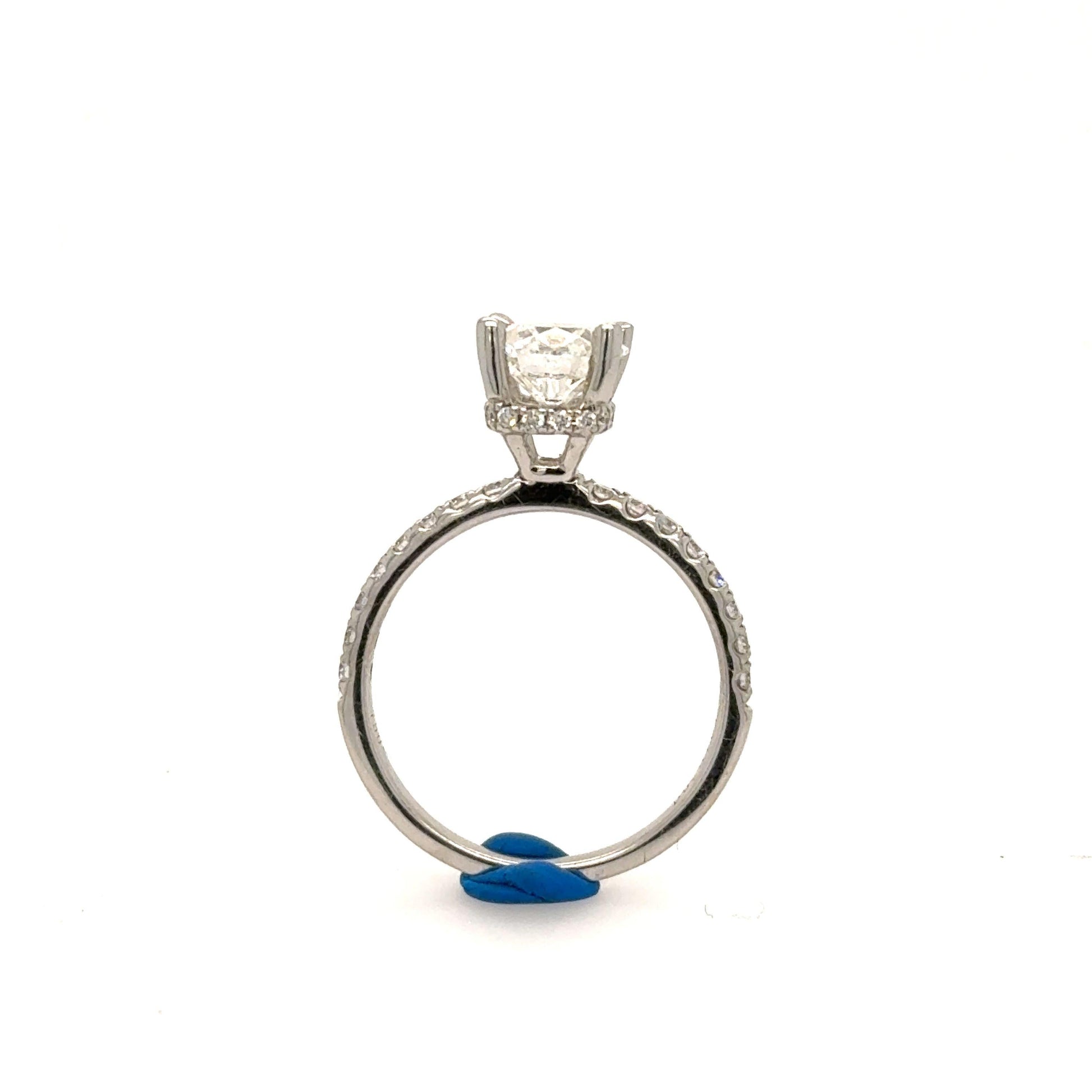 White gold engagement ring with round solitaire in four-prong setting and pavé band.