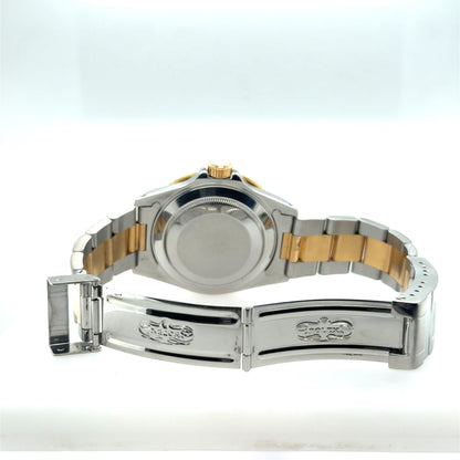 Two-tone stainless steel and yellow gold Submariner with open Fliplock clasp, caseback visible.