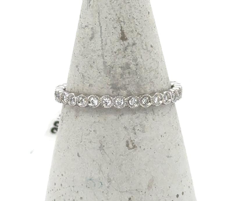 White gold eternity band with bezel-set round diamonds and milgrain detailing.