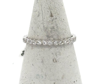 White gold eternity band with bezel-set round diamonds and milgrain detailing.