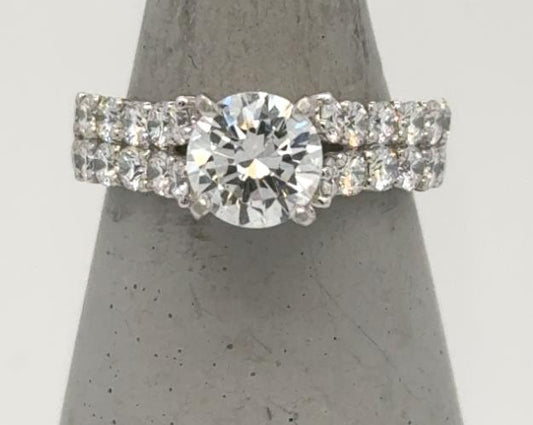 18K white gold ring with round solitaire and double-row shared-prong diamond band.