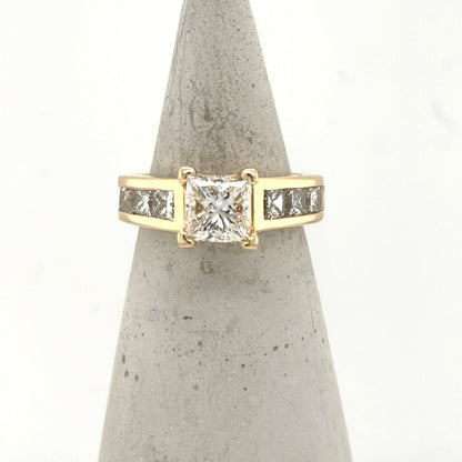 14K yellow gold ring with princess-cut center diamond and channel-set side stones.