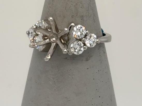 Platinum semi-mount ring with six round diamonds and empty center prong setting.