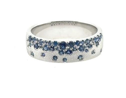 14K white gold band with scattered round blue sapphires burnish-set throughout.