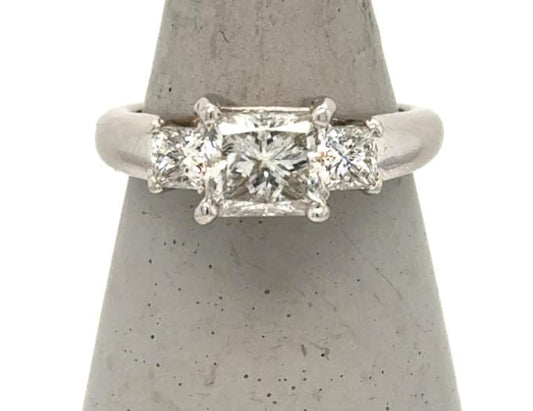 Platinum three-stone ring with princess-cut center diamond and two side diamonds.