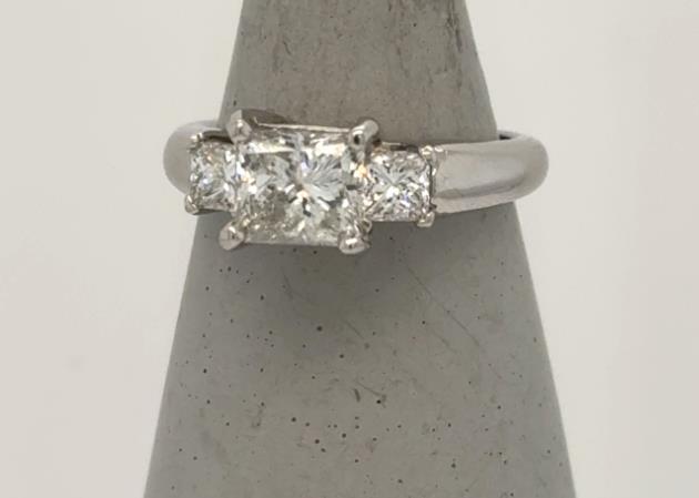 Platinum three-stone ring with princess-cut diamonds in prong settings on polished band.