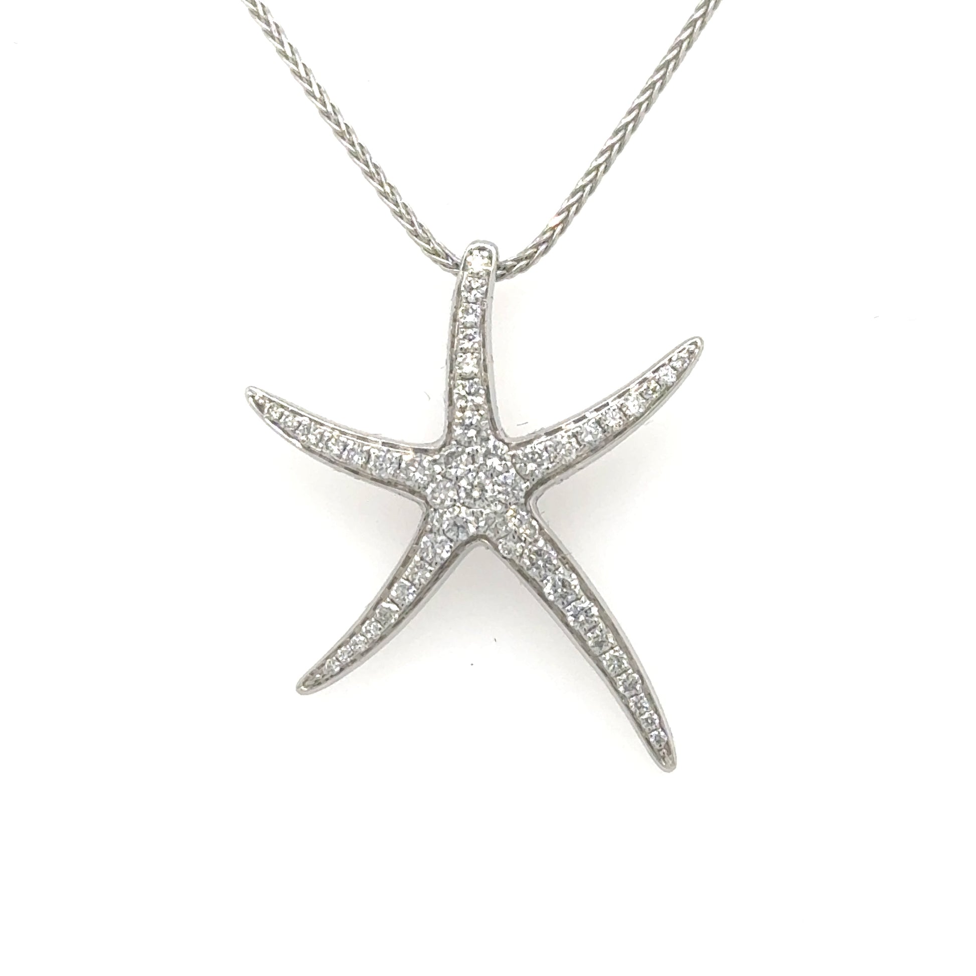 White gold starfish pendant paved with round diamonds, shown on a silver chain.